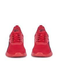 Para czerwonych sportowych butów marki Reebok z sznurowadłami, czarnymi akcentami po bokach i z logo na językach, pokazanych z przodu na białym tle.