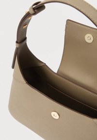 Beežist nahast käekott, millel on struktureeritud kuju, avatud ülaosa ja kuldsed metalldetailid. Omab avarat sisemust ja voodritaskut.