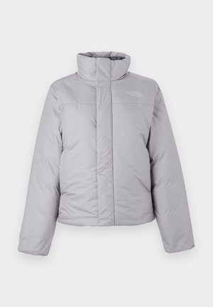 Doudoune gris clair avec un col montant, une fermeture éclair frontale et des surpiqûres horizontales. Elle présente un logo sur le côté gauche de la poitrine et des manches longues.