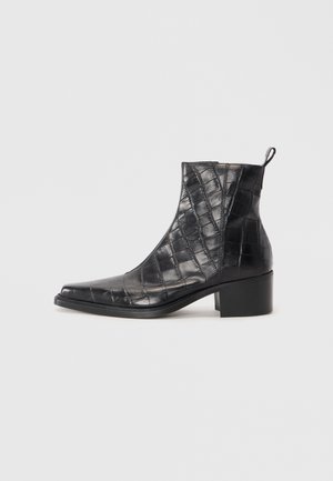 Botines negros de tobillo hechos de cuero sintético texturizado con un patrón de cocodrilo, que cuentan con una puntera cuadrada y un tacón ancho.