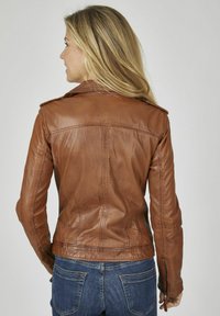 Braune Lederjacke mit taillierter Passform, mit einem Kragen und gesteppten Details. Getragen über blauen Jeans, die eine elegante Silhouette präsentieren.