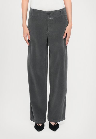 Pantalons en velours côtelé gris à jambes larges avec fermeture à bouton et passants de ceinture, présentant un tissu texturé et une coupe décontractée, associés à des talons noirs.