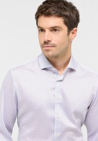 Camicia azzurra chiara con bottoni, caratterizzata da un motivo geometrico con accenti viola e bianchi, realizzata in un tessuto liscio e intrecciato.