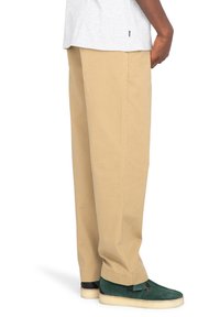 Khaki chino nohavice s voľným strihom, s hladkou textúrou a rovnými nohavicami. V kombinácii so zelenými mokasínovými topánkami.