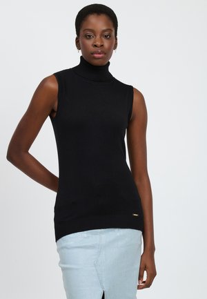 Pull sans manches noir à col roulé avec des détails côtelés en bas, fabriqué en tissu lisse, associé à une jupe en denim bleu clair.