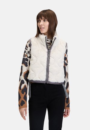 Weißes gesteppte Weste mit hohem Kragen, weichem Stoff und grauen Besätzen, kombiniert mit einem gemusterten Langarmoberteil mit braunen und schwarzen Leopardenmotiven.