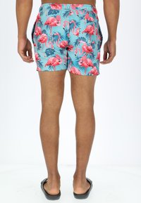 Swim shorts in light blue with a flamingo and palm tree pattern, featuring an elastic waistband and side pockets.