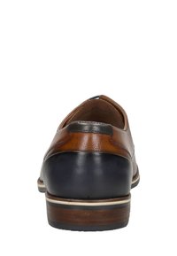 Chaussure en cuir marron et marine avec un dessus texturé, un talon lisse et une semelle en bois. Présente un onglet de talon noir et des coutures contrastantes.