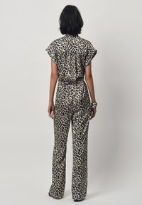 Lepardprint jumpsuit in beige en zwart, met korte mouwen, een relaxte pasvorm en wijde broekspijpen met een gegarneerde taille. 