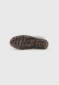 Semelle de chaussure avec une texture robuste, présentant une base transparente et un motif léopard noir, de forme arrondie et avec un crantage défini.