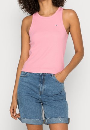 Un débardeur rose sans manches avec un col rond et un petit logo. Associé à un short en denim bleu clair, avec des ourlets retroussés et une coupe décontractée.
