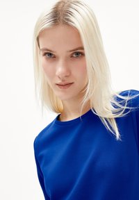 Blå crew-neck topp med en slät, stretchig textur. Tätt sittande silhuett med enkla, rena linjer och sömlös design.