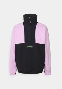 Mustaa ja vaaleanpunaista fleecepaitaa, jossa on korkea kaulus, puoli-vetoketju ja etulogo. Ominaisuuksia ovat väriblokkimuotoilu, sileä pinta ja ribbokirajaus.