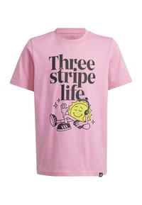 T-shirt en coton rose avec un texte noir audacieux "Three stripe life" et un personnage de soleil cartoon avec des écouteurs, se détendant à côté de chaussures.