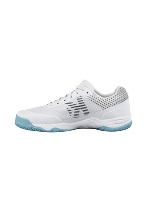 Zapatilla deportiva blanca con suela azul claro, logo geométrico negro en el lateral y cuello del talón estampado en negro y blanco.