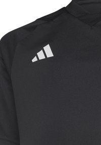 Maglietta sportiva nera realizzata in tessuto morbido; presenta un collo testurizzato e un logo bianco a tre strisce ben visibile sulla spalla sinistra superiore.
