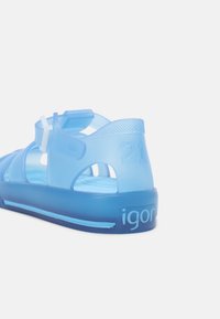 Transparent blue sandal with adjustable strap, textured heel, and cut-outs for ventilation. Features "21" on the back and "igor" branding.