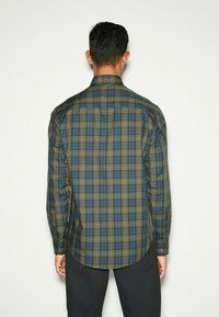 Langärmliges karriertes Hemd in Dunkelgrün und Blau, mit gelben Akzenten, Button-Down-Kragen und abgerundetem Saum. Hergestellt aus leichtem Stoff.