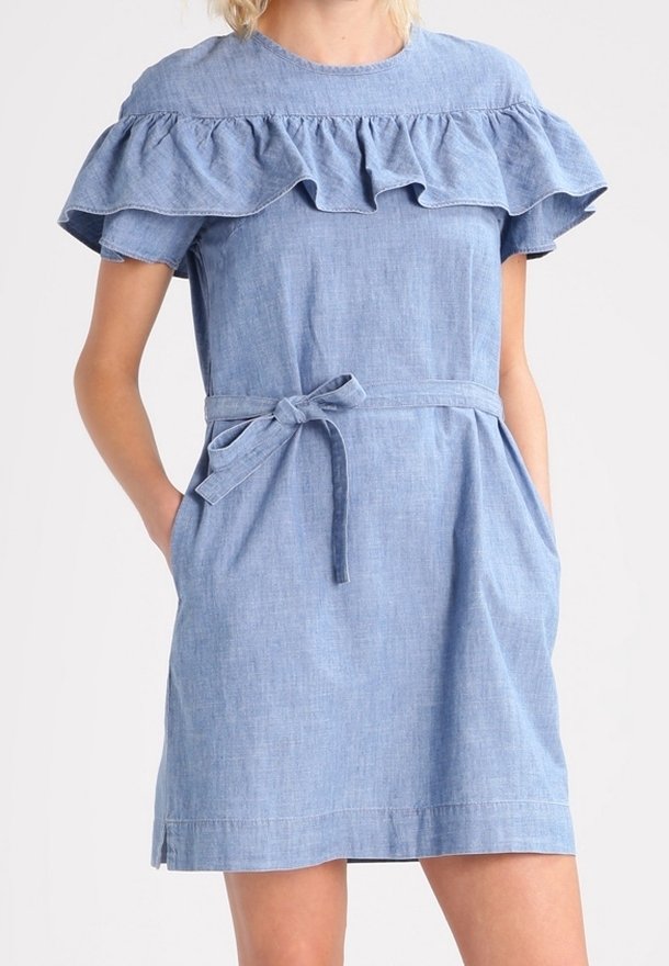 Robe en denim bleu clair avec un col volanté, des manches courtes, une taille à nouer et des poches sur les côtés. Design simple et ajusté avec une texture lisse.