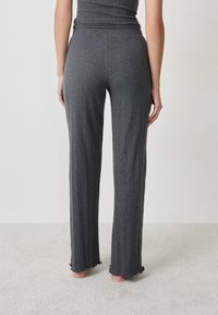 Grijze geribbelde gebreide brede broek met een rafelige zoom en een elastische tailleband, die zorgt voor een comfortabele pasvorm en een gestructureerde uitstraling.
