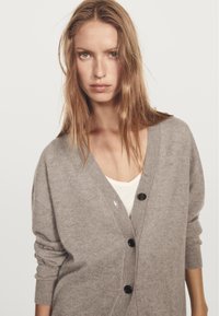 Khaki kashmircardigan med v-ringning, långa ärmar och sex svarta knappar fram. Slät textur, avslappnad passform och mjuk fall.