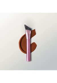 Pinceau à maquillage incliné avec poils noirs et blancs et manche rose reposant sur une traînée de crème marron sur un fond clair.