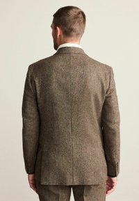 Brown tweed blazer with a textured finish, notched lapels, and two-button closure; features a vent at the back and buttoned cuffs.