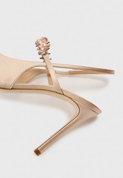 Beżowe satynowe sandały na wysokim obcasie z zaostrzonym noskiem, cienkimi paskami i ozdobą z biżuterii przy kostce. Gładka tekstura i elegancki design.