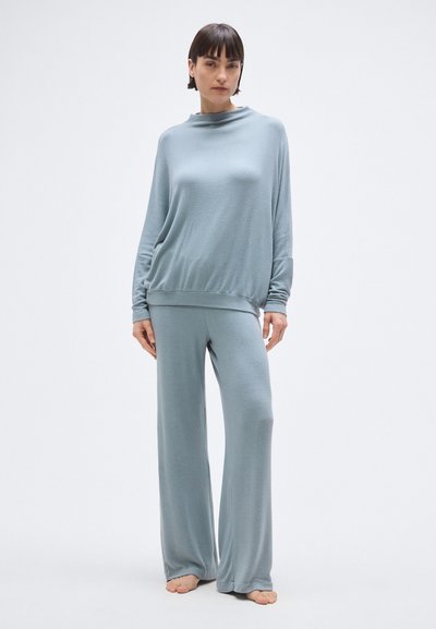 Világoskék otthoni viselet szett puha anyagból; laza felső magas nyakkivágással és széles szárú nadrágokkal.