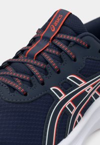 Μπλε αθλητικό παπούτσι με διχτυωτό ύφασμα, κόκκινες λεπτομέρειες και λευκή καουτσούκ σόλα. Διαθέτει υφασμάτινο σχέδιο κορδονιών και λογότυπο Asics στη γλώσσα.