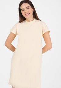 Abito crema a maniche corte con colletto alto e vestibilità rilassata, realizzato in tessuto morbido, che arriva a metà coscia.
