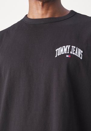 Černé bavlněné tričko s malým bílým vyšitým logem "TOMMY JEANS" na levé části hrudi. Kulatý výstřih a krátké rukávy.