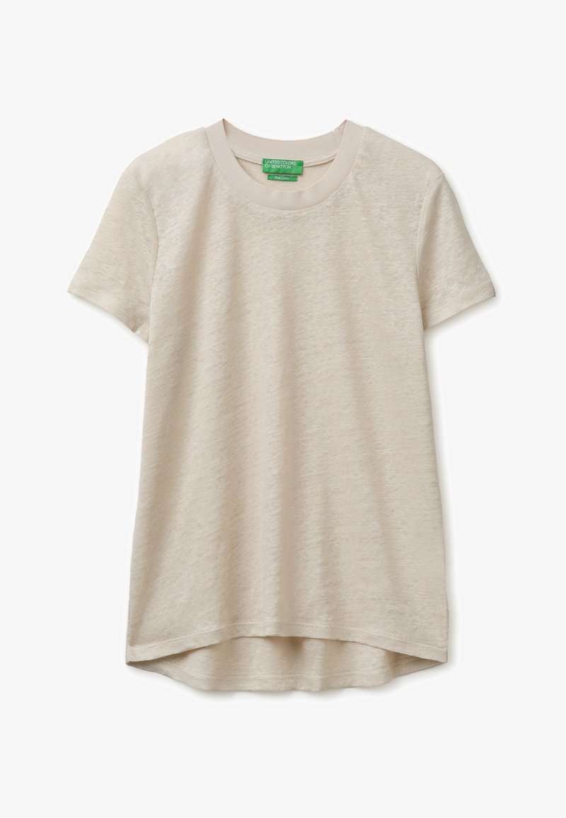 Camiseta beige de manga corta con cuello redondo, dobladillo trasero ligeramente más largo y etiqueta de marca visible en verde dentro del cuello.