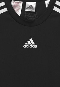 Czarna koszulka sportowa wykonana z oddychającego materiału. Posiada białe logo Adidas oraz trzy białe paski na ramionach. Metka zawiera informacje o rozmiarze i instrukcje pielęgnacji.