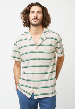 Camicia a maniche corte color crema con righe verdi, realizzata in tessuto testurizzato. Presenta un design con bottoni e una tasca sul petto.
