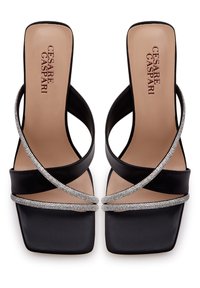 Sandales à talons hauts noires avec des lanières croisées ornées de décorations argentées, un design à bout carré et une texture en cuir lisse.