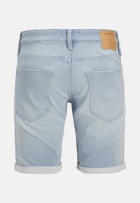 Short en jean bleu clair avec revers roulés, deux poches arrière, passants de ceinture et un patch en cuir marron à la taille.