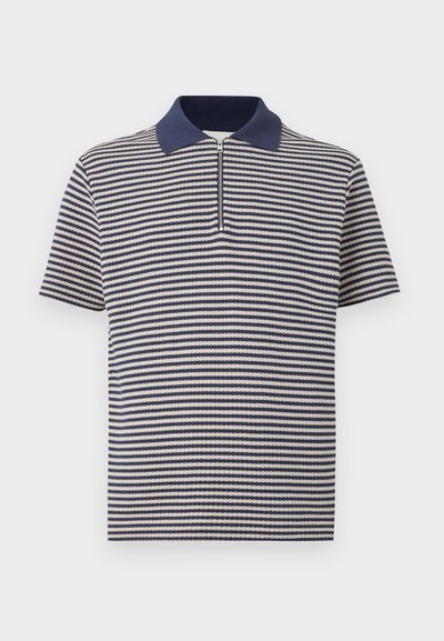 Κοντομάνικο πόλο μπλουζάκι με οριζόντιες ρίγες σε ναυτικό μπλε και λευκό, με γιακά σε ναυτικό μπλε και μισό φερμουάρ μπροστά.