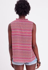 Mouwloze top met een kleurrijk geometrisch patroon in roze, paars en geel, voorzien van een gerimpelde kraag en plissé-details aan de achterkant.
