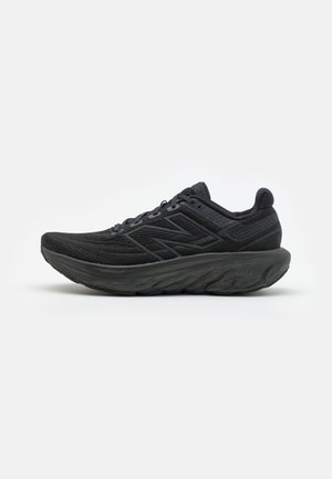 Czarny sportowy but do biegania z grubą amortyzowaną podeszwą i siateczkową cholewką, z dużym logo New Balance po boku.