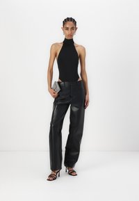 Czarny body na ramiączkach z wysoko wyciętym dekoltem, połączone z czarnymi, wysokim stanem spodniami z imitacji skóry. Uzupełnione srebrną torebką o teksturowej powierzchni i czarnymi sandałkami na obcasie.