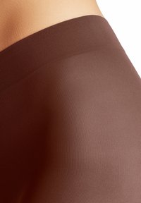 Leggings marron à côtes fabriqués dans un tissu lisse et extensible. Dotés d'une taille haute et d'un design sans coutures pour plus de confort.