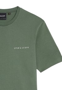 Olivengrøn bomulds t-shirt med rund hals, med hvid "LYLE & SCOTT" tekst på venstre brystområde og korte ærmer.