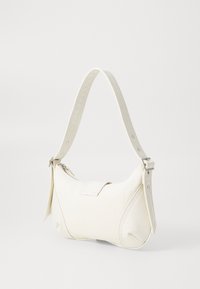 White canvas handbag with a textured strap, curved shape, zipper closure, and contrasting mesh accents on the sides.