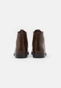 Bruine leren enkelboots met een gladde afwerking, elastische zijpanelen en trekstangen, met een zwarte rubberen zool.