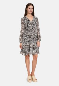 Bloemenprint jurk met een v-hals, lange mouwen en een geassembleerde taille. Gemaakt van lichtgewicht, doorzichtig materiaal in zwart, crème en zachte roze tinten.
