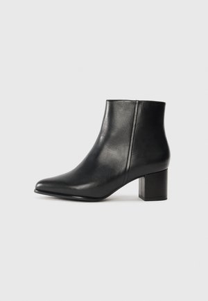 Botte de cheville en cuir noir avec un bout pointu et un talon bloc. Texture lisse et détails de couture minimalistes sur le dessus.