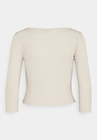 Beige ribbad långärmad topp med fyrkantig halsringning och figurnära design. Tyget verkar mjukt med en slät textur och minimala sömmar.