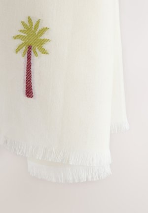 Biela tkaná látka s třásňami na okrajoch, na ktorej je malý vyšívaný palmový strom s hnedým kmeňom a zelenými listami.