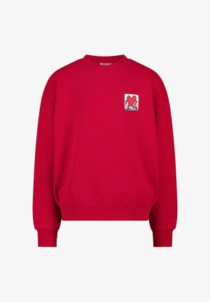 Sweatshirt rouge en coton, présentant un col rond et des poignets côtelés. Affiche un patch carré avec un graphique de cœur dans le coin supérieur gauche.